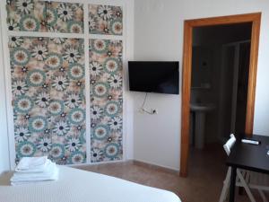 1 dormitorio con pared y TV. en Miramar Habitaciones, en Calabardina