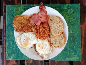 un plato de desayuno con huevos tocino y pan en Home @ Harry's, en Pretoria