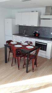 een keuken met een zwarte tafel en stoelen en een keuken met witte kasten bij Appartement Laduna , Résidence Ventura in Tarifa