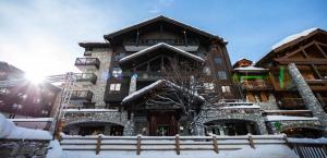 een groot gebouw met sneeuw op de grond bij Avenue Lodge Hotel & Spa in Val dʼIsère