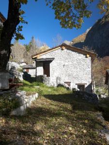 a stone building with a tree in front of it at Baite La Pedruscia in Val Masino