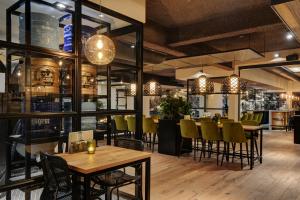 a restaurant with tables and chairs and a bar at Strandhotel Vigilante in Makkum
