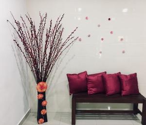 um banco com almofadas vermelhas e um vaso com flores em Bukit Katil Indah Homestay em Malaca