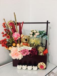 ein Teddybär, der in einer Kiste mit Blumen sitzt in der Unterkunft Bukit Katil Indah Homestay in Malakka