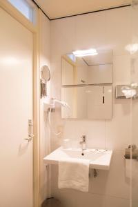 a white bathroom with a sink and a mirror at Strandhotel Vigilante in Makkum