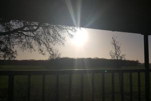 a sun shining in the sky behind a fence at Erve 't Hacht in Ane