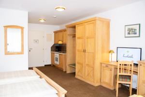 a bedroom with a bed and a desk and a kitchen at Landhotel Post Ebensee am Traunsee ***S in Ebensee