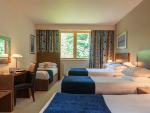 una camera d'albergo con tre letti e una scrivania di Ballyroe Lodge a Tralee