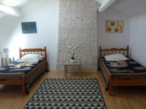 2 camas en una habitación con una pared de ladrillo en Les Tuileries, en Ponteyraud
