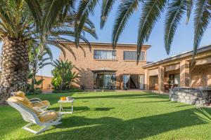a yard with two chairs and a palm tree at Chala-Kigi Apartments in Swakopmund