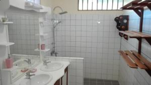 a white tiled bathroom with two sinks and a shower at Cayenne - 2313 Route de la Madeleine in Cayenne