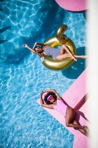 twee vrouwen op een vlot in een zwembad bij Tropicana Ibiza Suites - Adults Only in Playa d'en Bossa