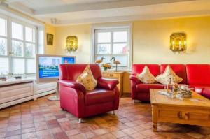 a living room with red chairs and a tv at Haus Seelord, Whg. Kapitän in Braderup