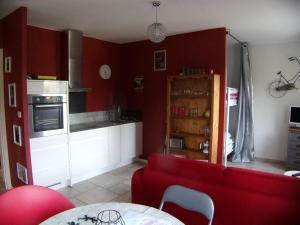 uma cozinha com paredes vermelhas e um sofá vermelho em Gîte du Gecko em Saint-Christol-lès-Alès