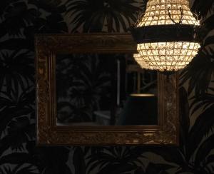 a mirror on a wall with a lamp and a light at Hôtel Le G (ex Le Genève) in Nice