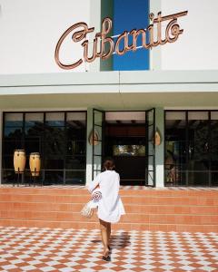 a woman in a white dress walking in front of a building at Cubanito Ibiza in San Antonio +34 photos