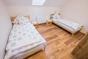 two beds in a room with a wooden floor at Dwór Skalny Apartamenty, Pokoje i Restauracja Karczma Skalna in Miłków