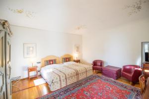 a bedroom with a bed and two chairs and a rug at Castello Rosso in Costigliole Saluzzo