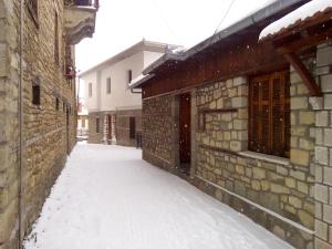 Une allée couverte de neige à côté d'un bâtiment dans l'établissement To Patriko Tou Saranti, à Metsovo