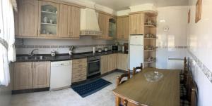 kuchnia z drewnianymi szafkami, stołem i lodówką w obiekcie CASA AUREA DE CACHEIRAS w mieście O Grove