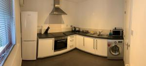 a kitchen with white cabinets and a washer and dryer at Aberdeen Serviced Apartments - Bloomfield in Aberdeen