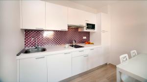 a white kitchen with white cabinets and a sink at Leo Canela in Isla Canela