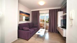 a living room with a purple couch and a tv at Leo Canela in Isla Canela