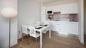a white kitchen with a white table and chairs at Leo Canela in Isla Canela