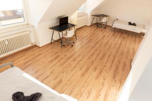 an attic room with a wooden floor and a desk at AVR Apartment Geestemunde 2 in Bremerhaven