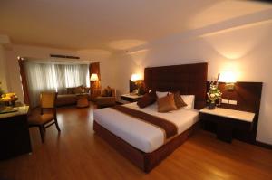 a bedroom with a large bed and a living room at Furama Chiang Mai in Chiang Mai