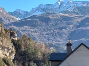 una casa con chimenea y montañas al fondo en APARTAMENTOS LÁZARO-Calle Iglesia 8 - 1º C en Escarrilla