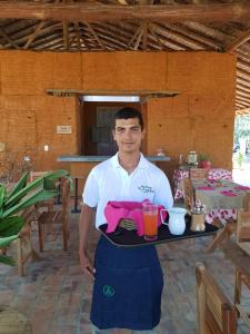 
a man holding a tray of food in front of a table at Nativo Glamping in Barichara
