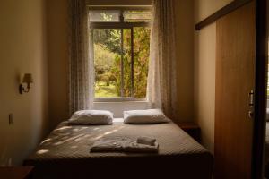 Cama en habitación con ventana en Pousada Betânia en Curitiba