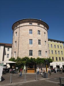 un gran edificio de ladrillo con gente caminando delante de él en Torrione Trento, en Trento