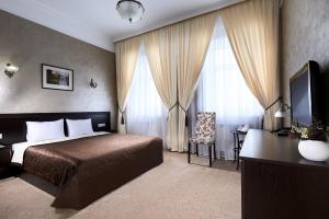 Un dormitorio con una cama, un escritorio y un televisor. en Hotel Imperial Wellness & SPA, en Obninsk