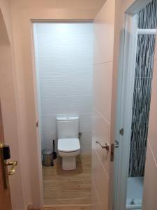 a white toilet sitting in a bathroom next to a door at Hostal Restaurante Cornella in Cornellà de Llobregat