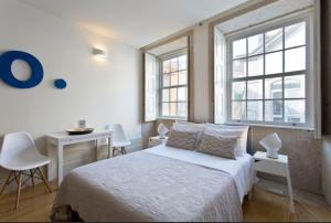 1 Schlafzimmer mit einem Bett, einem Schreibtisch und 2 Fenstern in der Unterkunft Vitoria Studio Residence II - Downtown in Porto