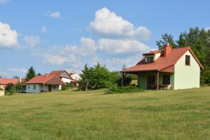 a house with a red roof in a field at Domki nad jeziorem - Posiadłość Nad Zatoką in Ryn