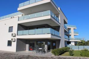 a white building with blue balconies and a table at Apartmani Uwe in Banjole +3 photos