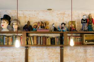 a wall with shelves filled with books and dolls at Pars Teatro Hostel in Barcelona