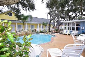 a swimming pool with white chairs and a house at D&R Pelican Bay Resort in Rockport
