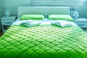 - un lit avec une couette verte et 2 oreillers dans l'établissement Apartment Pluvia, à Osijek