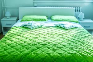 een bed met een groen dekbed en 2 kussens bij Apartment Pluvia in Osijek