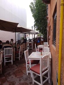 a group of tables with white chairs and umbrellas at Hotel Meson Mariano Matamoros in Querétaro