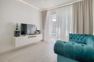 uma sala de estar com um sofá azul e uma televisão em LUX APARTMENT OCEAN GARDEN - PLAYA PARAISO - 2 Bedrooms, 2 Bathrooms, Big Terrace em Adeje