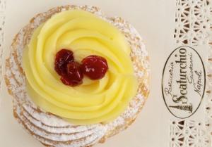 a small cake with yellow frosting and cherries on it at Da Polly a Piazza Amedeo in Naples