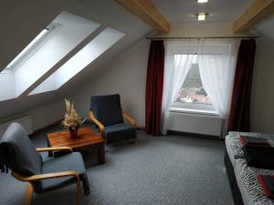 シュトランベルクにあるBílá hora Štramberkの椅子2脚、テーブル、窓が備わる客室です。