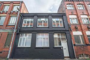 a black house with a white door in front of buildings at Mason Street Apartment Sleeps 16 in Manchester