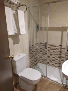 a white toilet sitting next to a shower in a bathroom at Hostal Restaurante Cornella in Cornellà de Llobregat