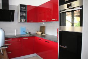 a red kitchen with black appliances and red cabinets at Ferienwohnung Palme in Trofaiach